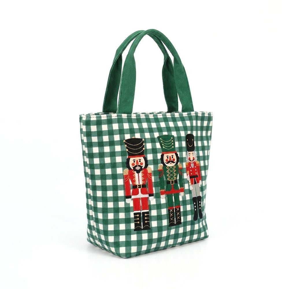 A green and white gingham canvas tote bag with dark green fabric handles, featuring three embroidered nutcracker figures on the front.