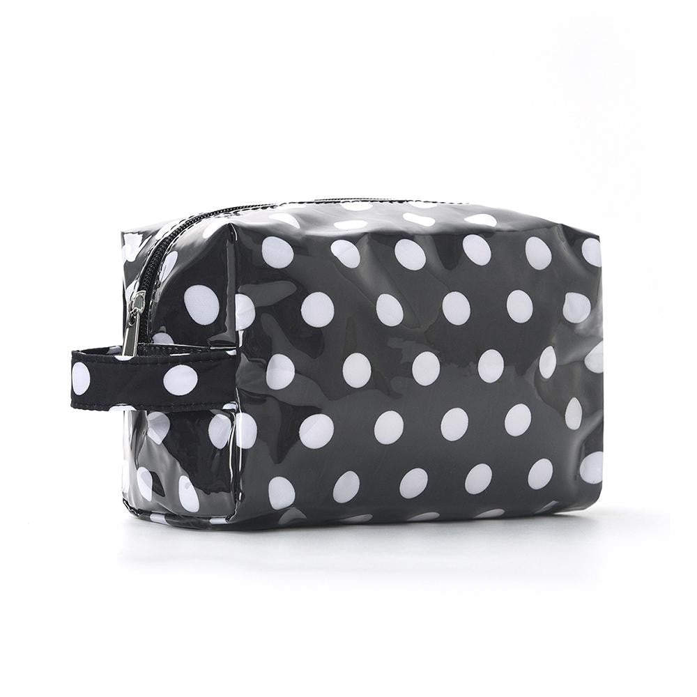 A glossy black and white polka dot cosmetic pouch with a top zipper and a matching wrist strap, shown on a clean white background.