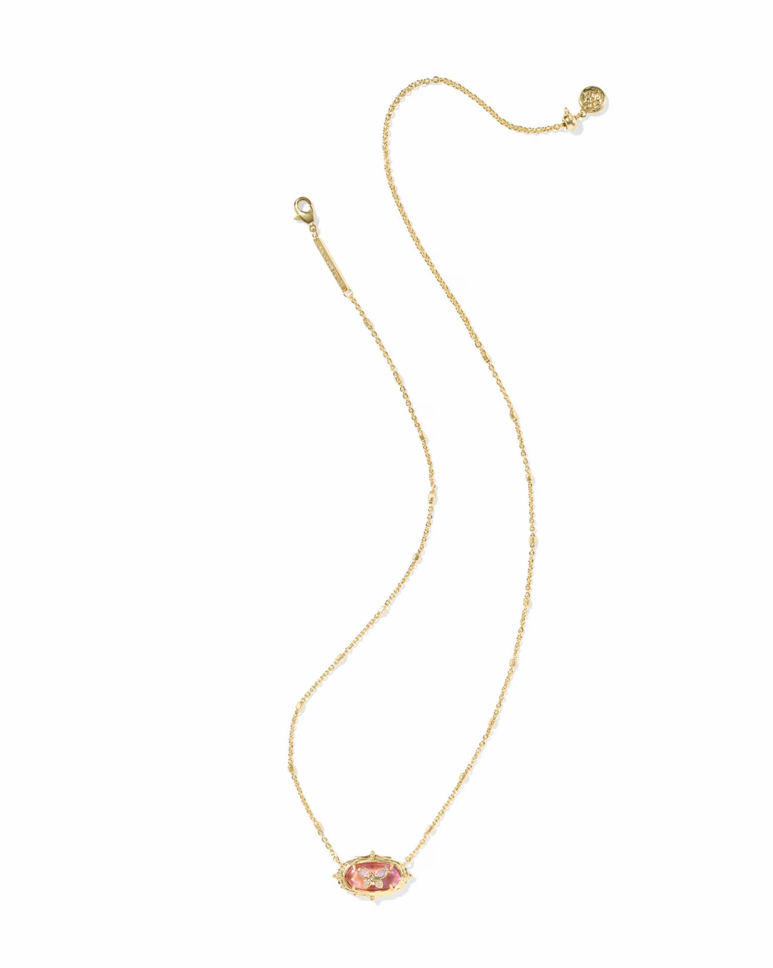 A delicate gold chain necklace featuring a small, horizontally oriented oval pendant with a pink enamel center and tiny clear stones around it, displayed on a solid white background.