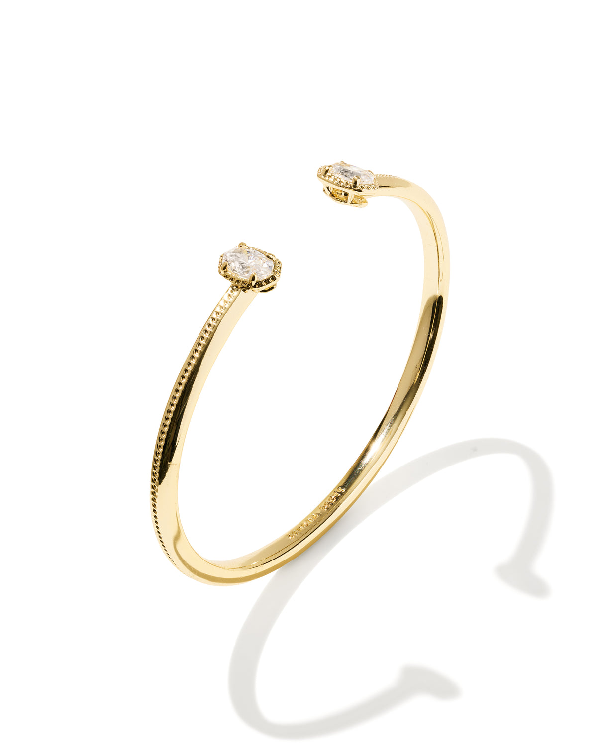 A gold open cuff bracelet with two small oval diamond settings, shown on a clean white background with a soft shadow.