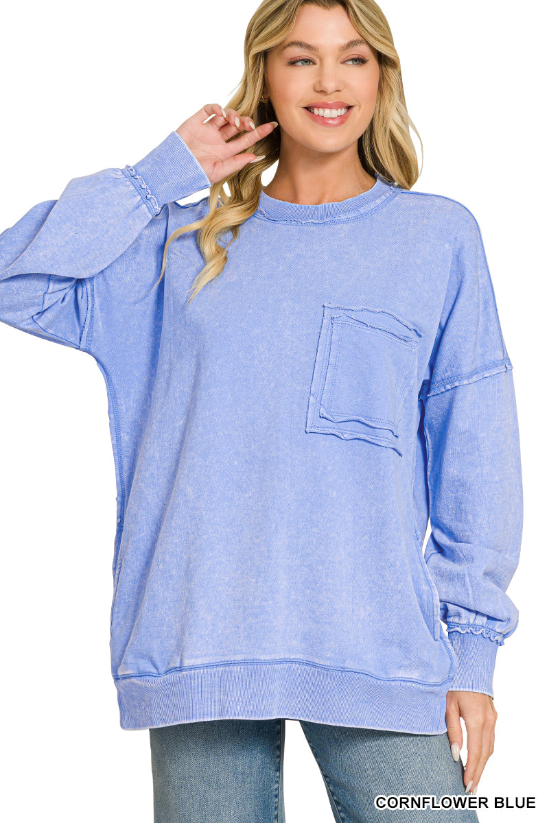 Woman wearing light blue acid wash pullover with a pocket on the chest with blue jeans on a white background