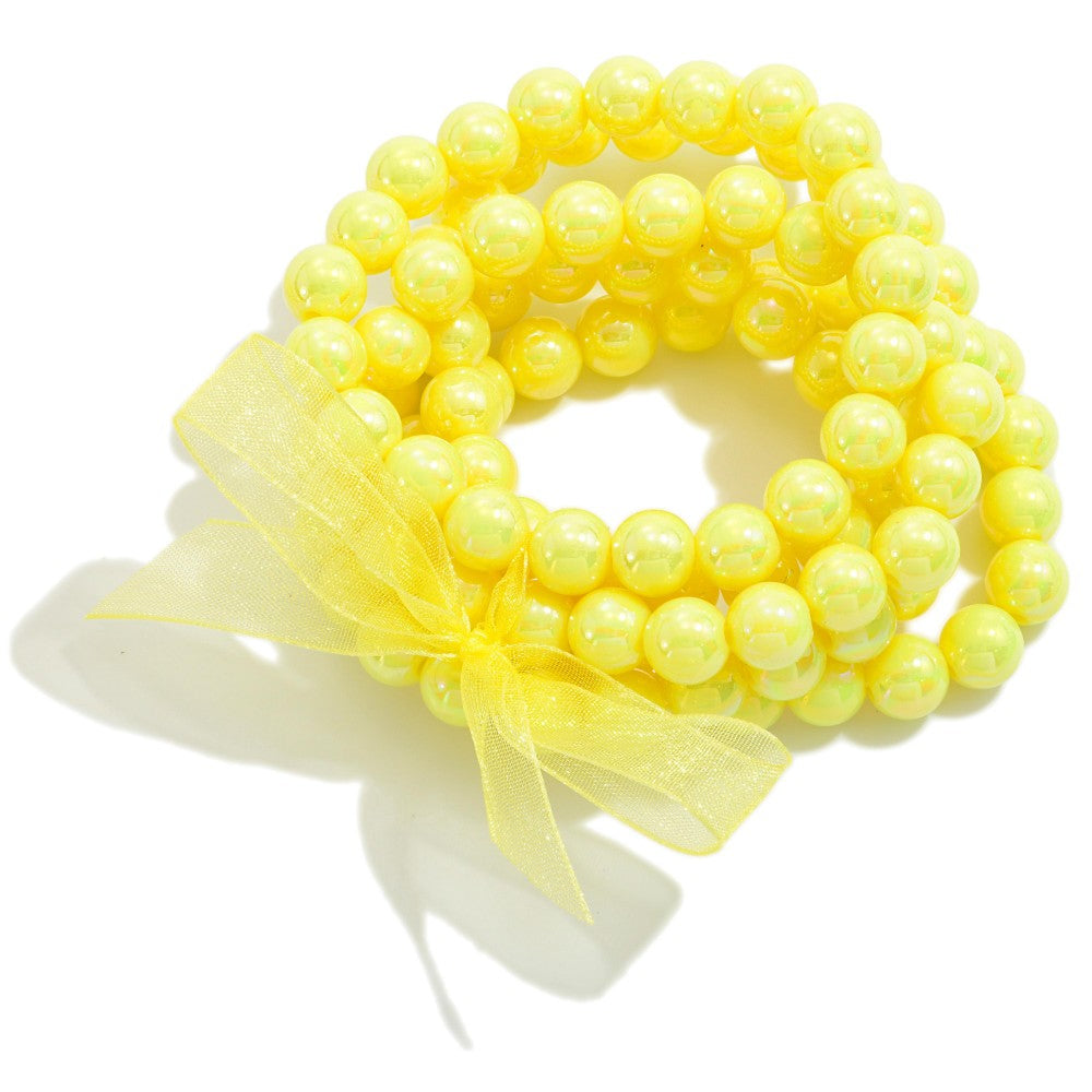 Yellow beaded bracelet set with a bow on a white background