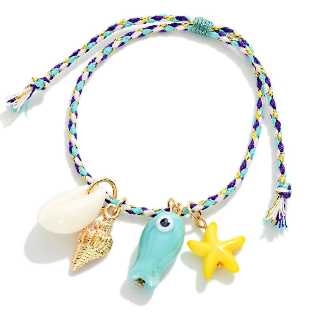 Colorful braided bracelet with shell, fish, and starfish charms on a white background