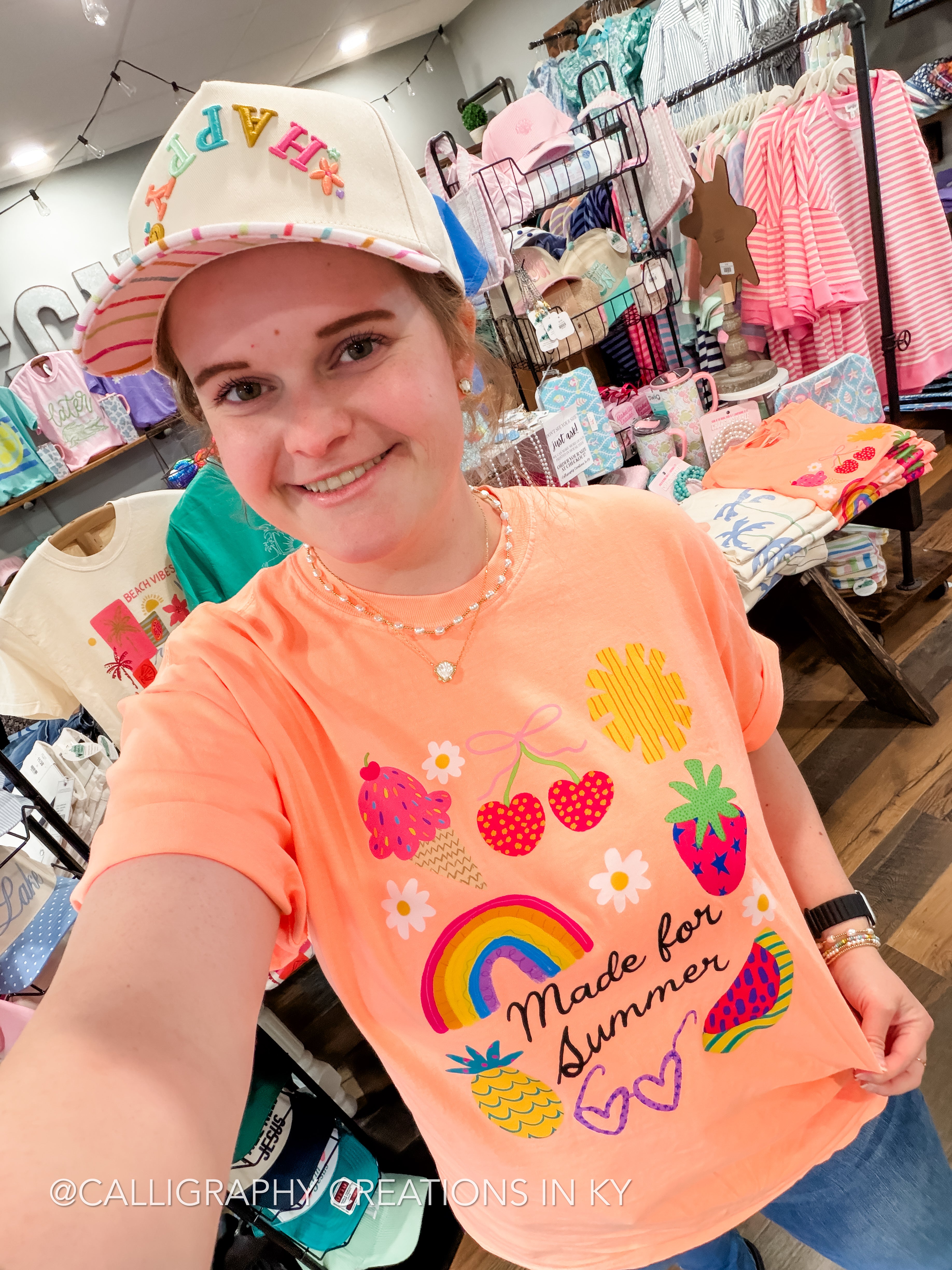 Girl wearing a neon cantaloupe short sleeve graphic tee that says “made for summer” with multiple summer icons on it