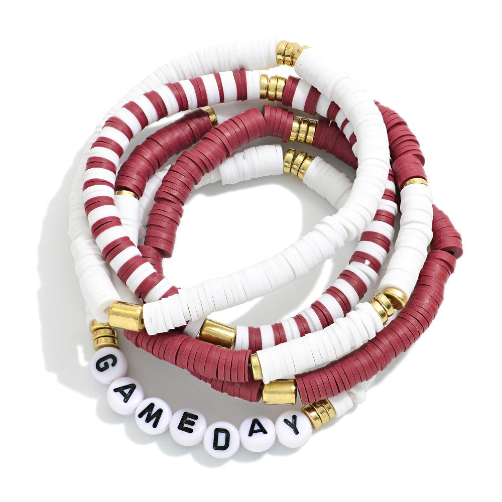 A stack of five beaded stretch bracelets on a white background. The bracelets feature alternating bands of solid burgundy and white disc beads, with some bracelets accented by gold metal spacers.