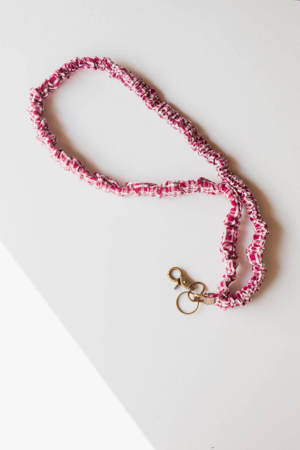 Maroon and white checked scrunchie lanyard with a gold clasp on white background