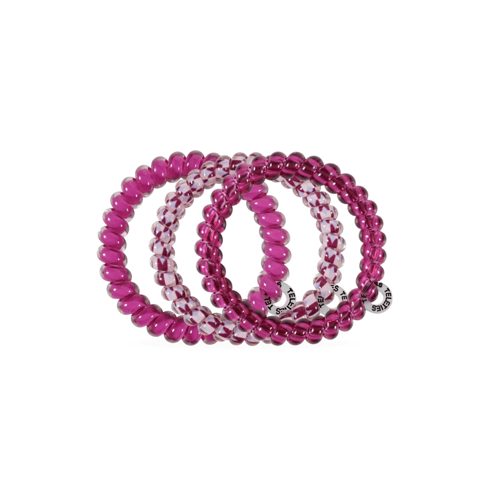 Three beaded stretch bracelets in shades of pink and magenta, including a marbled pink and white design and a silver-tone branded charm, displayed on a clean white background.