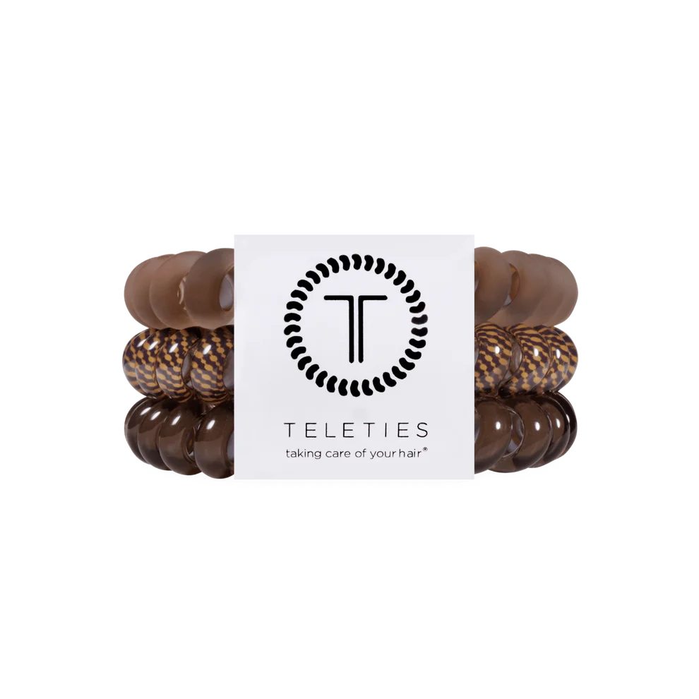 A set of four Teleties hair stretch bands in shades of brown, including solid medium brown, leopard print, dark brown, and glossy dark brown, wrapped around a white paper band with the Teleties logo.