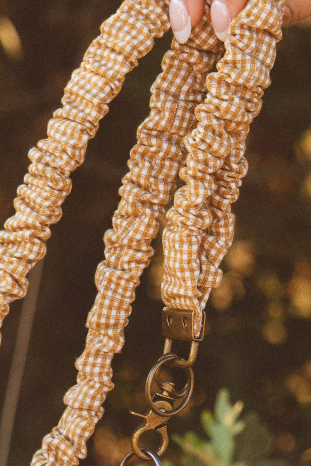 Mustard gingham scrunchie lanyard with a blurred background 