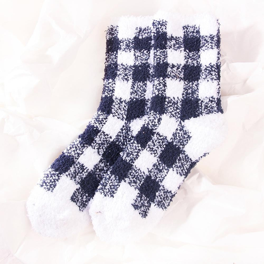 A pair of plush fuzzy socks in a navy blue and white buffalo check pattern, laid flat on a soft white fabric background.