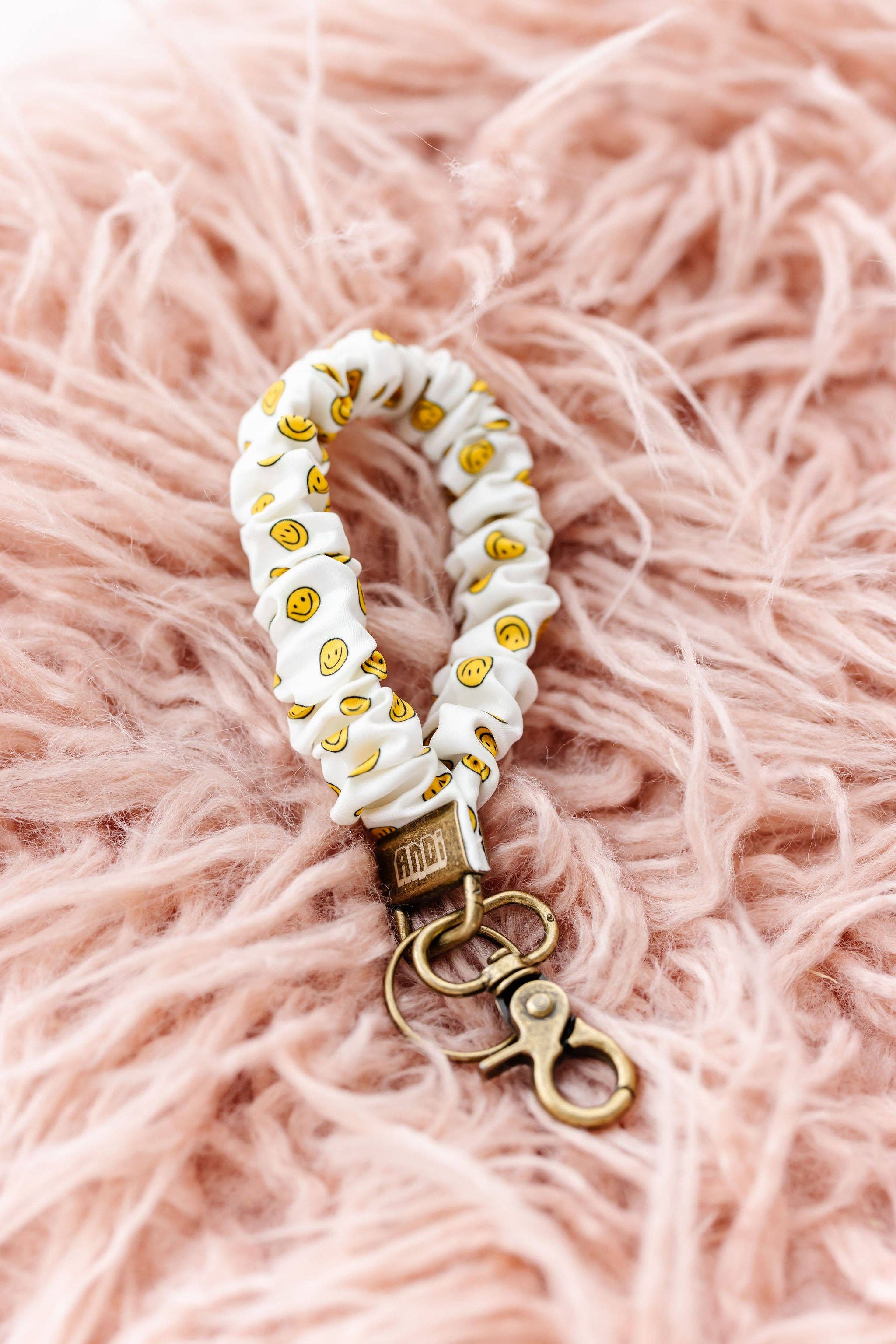 White scrunchie key chains with happy faces on a pink fluffy background 