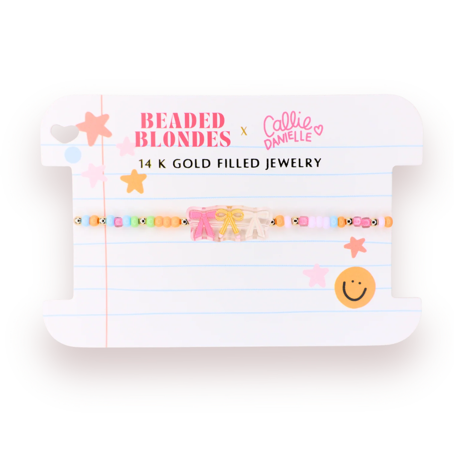 A beaded bracelet displayed on a branded white card. The bracelet features pastel-colored beads with small character details and two bow charms in pink and beige, suspended over a lined notebook-style card that reads 'BEADED BLONDES x Callie Danielle' and '14 K GOLD FILLED JEWELRY'.