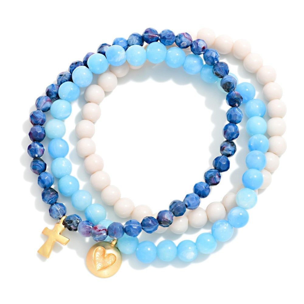 Set of blue and white beaded bracelets with gold charms on a white background