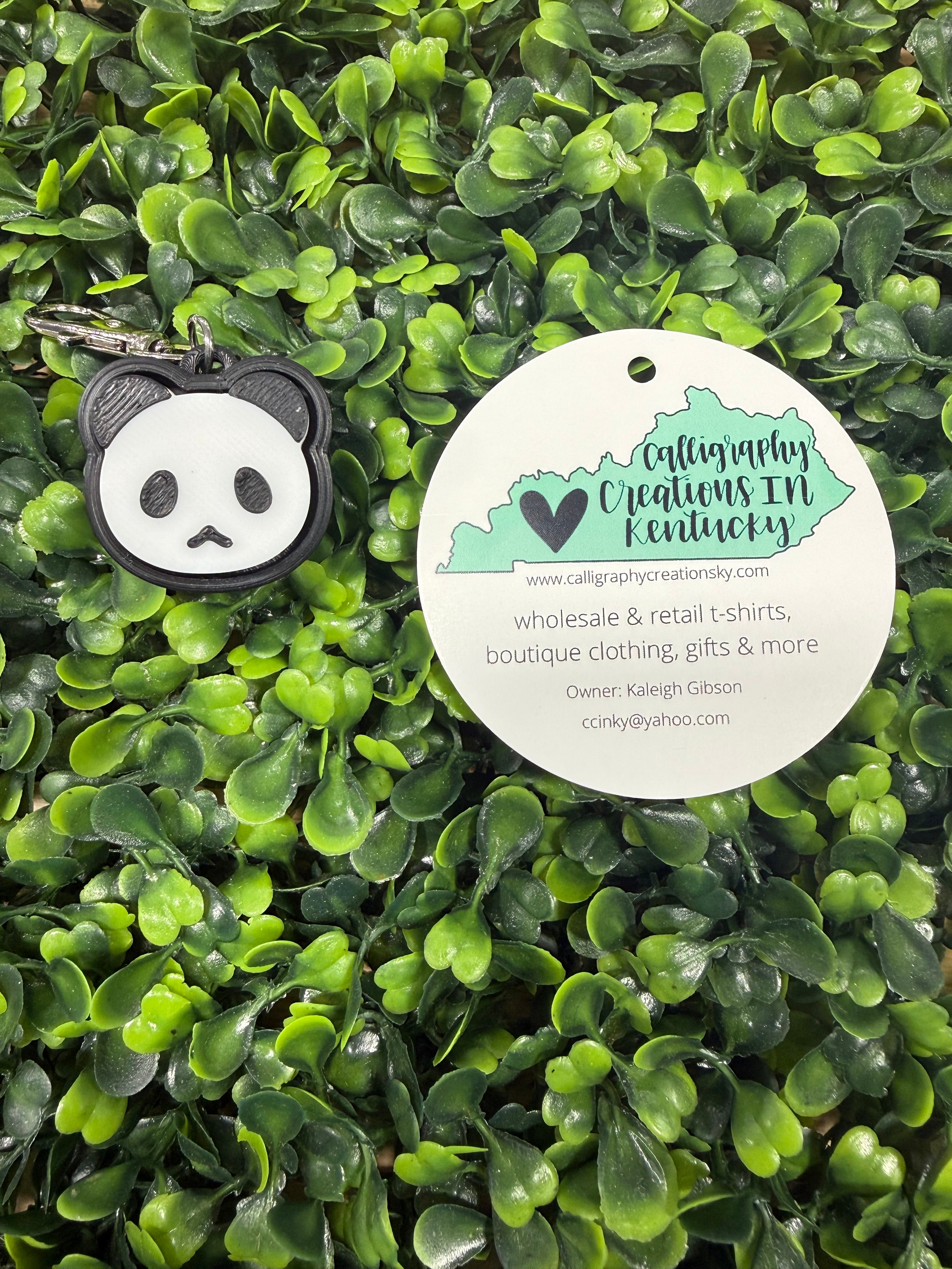 Keychain with panda design on a green leafy background