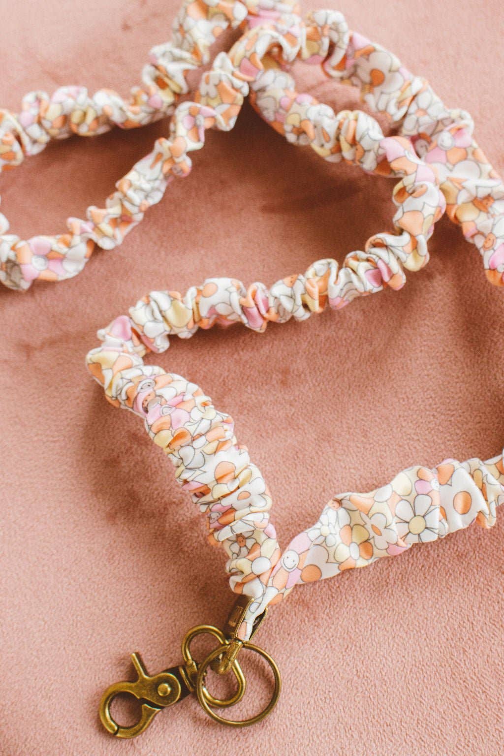 Flower patterned scrunchie lanyard with gold clasp on a pink velvet background 