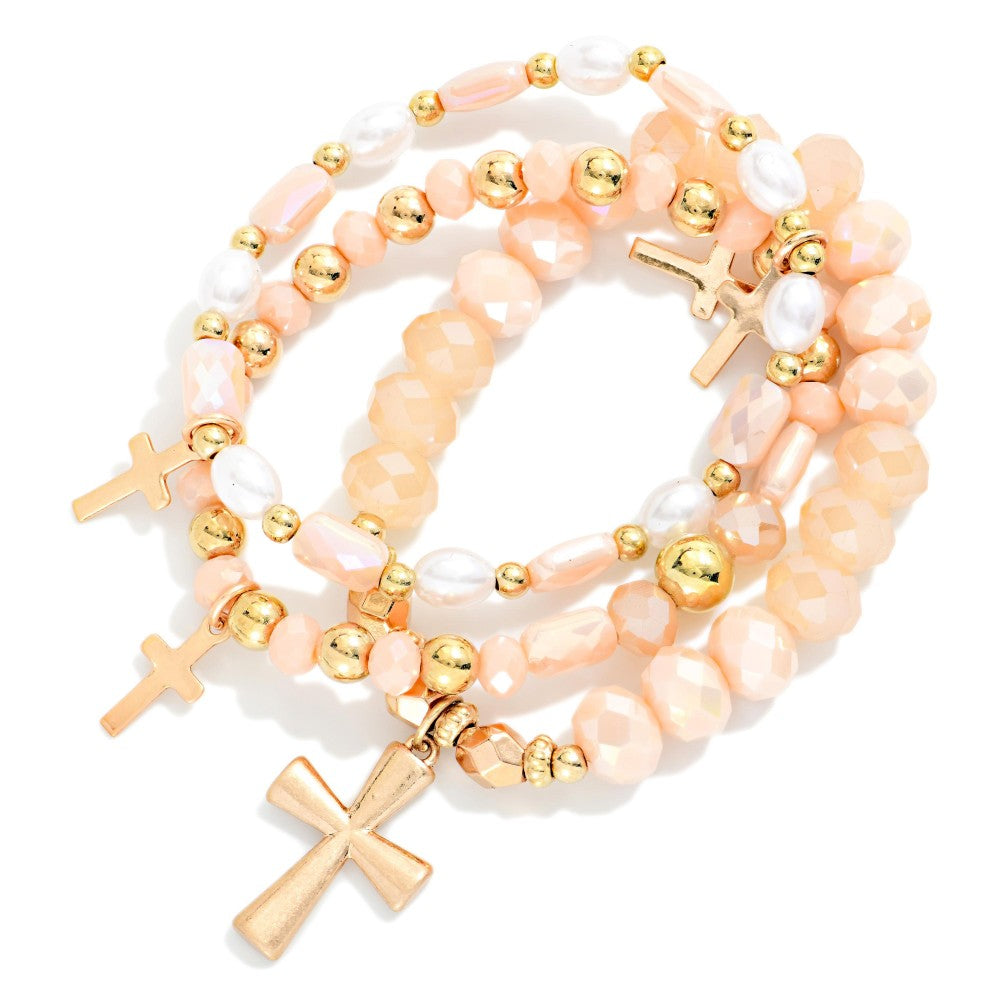 Three beaded peach and gold bracelets with cross charms. 