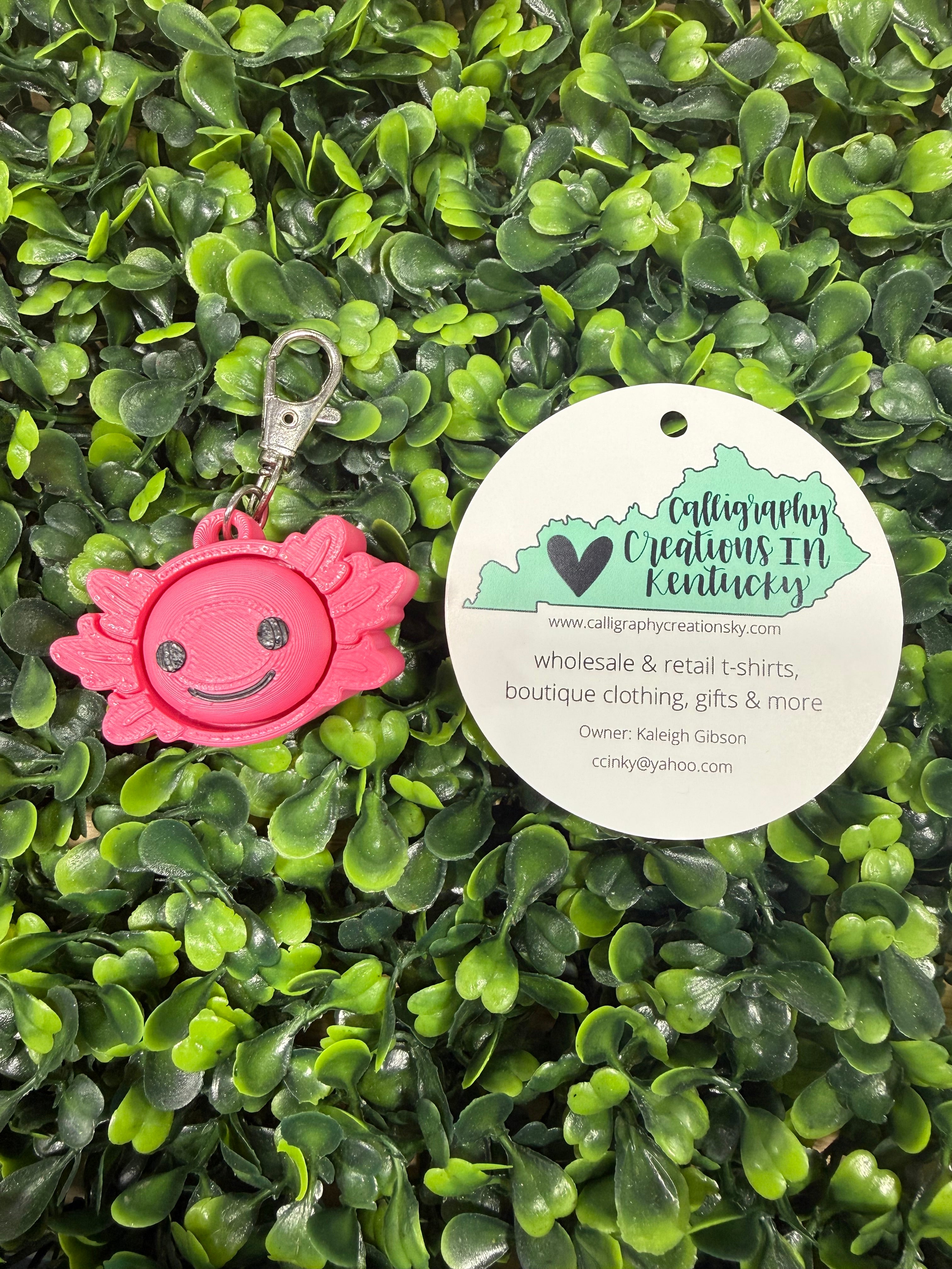 Pink keychain with a smiley face design on green artificial grass