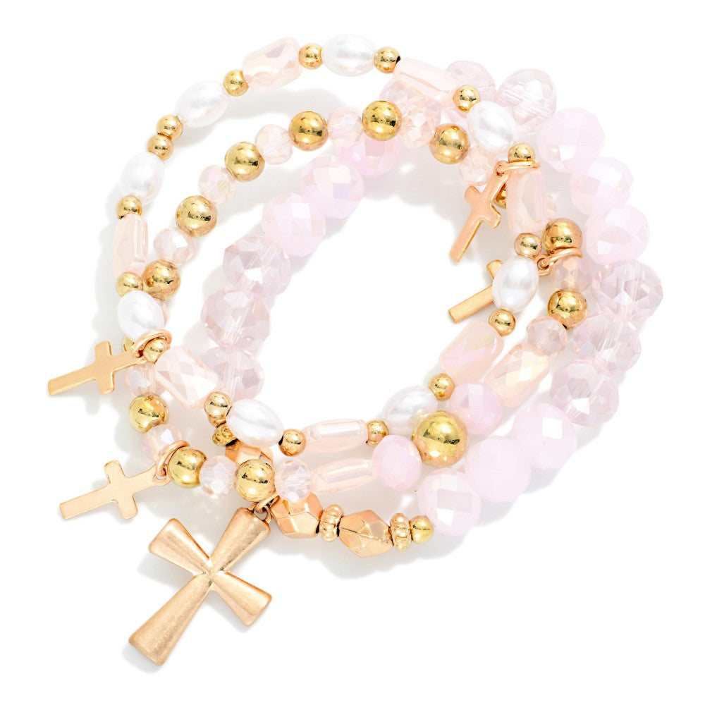 Three beaded pink and gold bracelets with cross charms. 