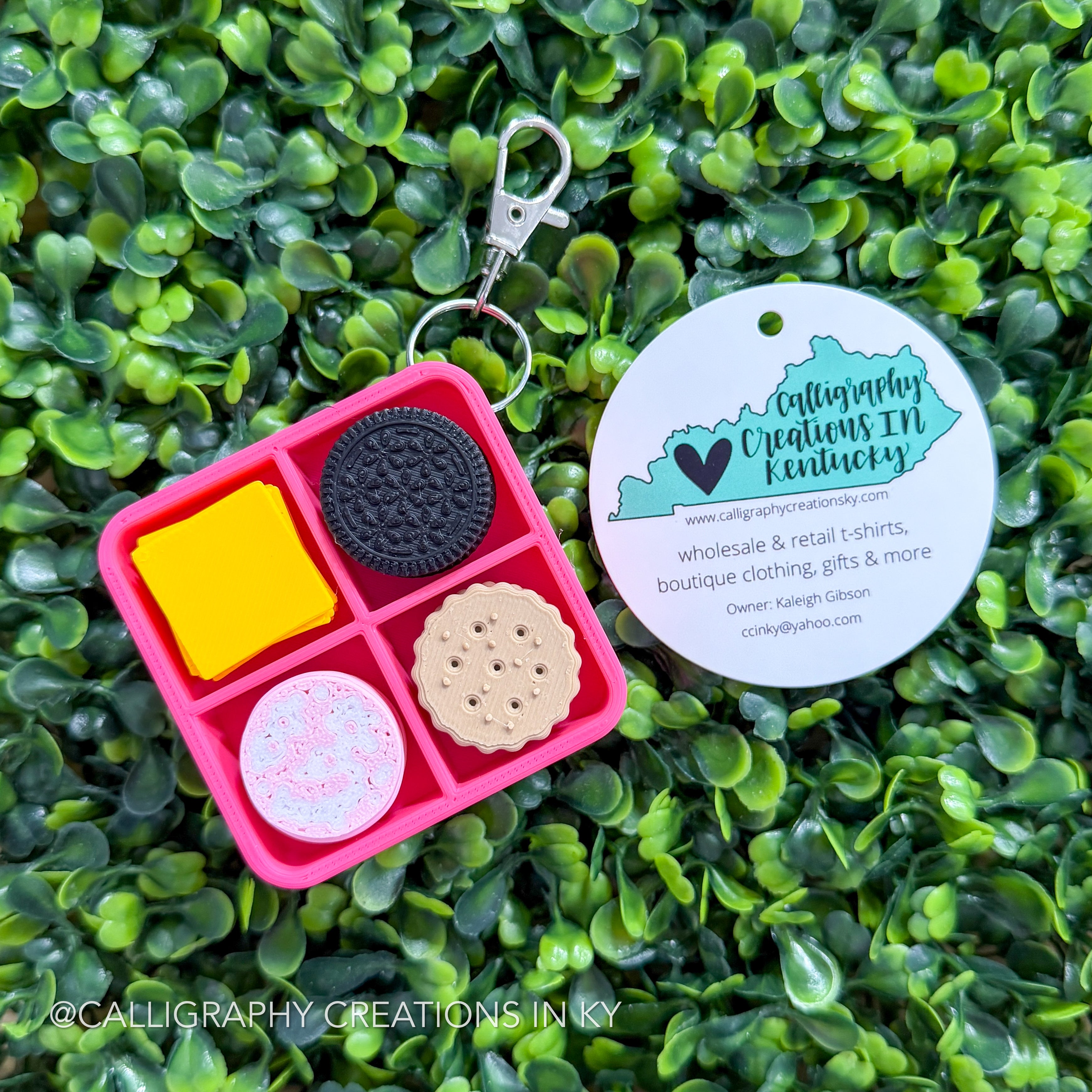Cheese, ham, crackers, cookies fidget key chain on greenery background with Calligraphy Creation branding