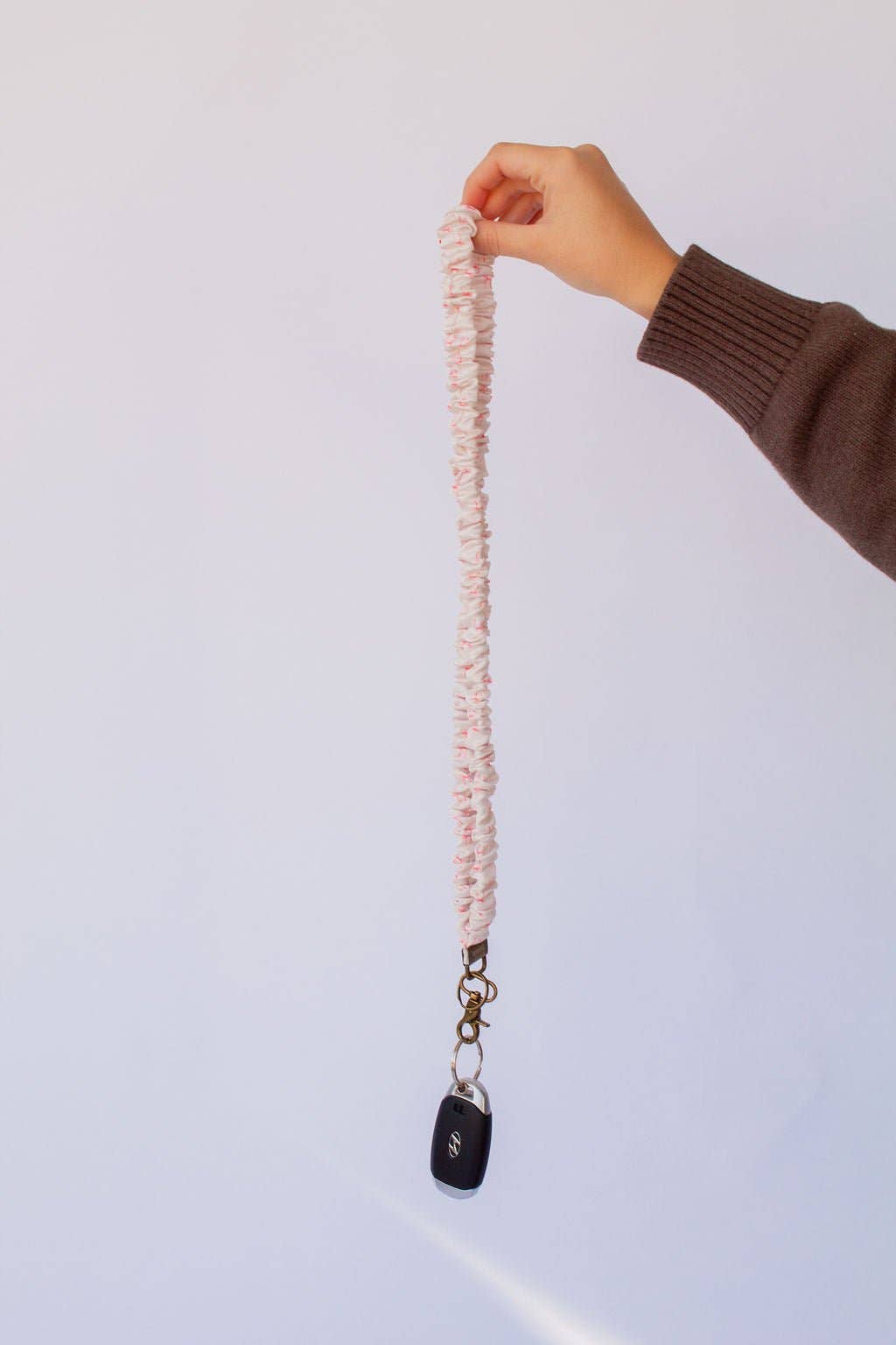 Woman holding white lanyard with pink bows on it