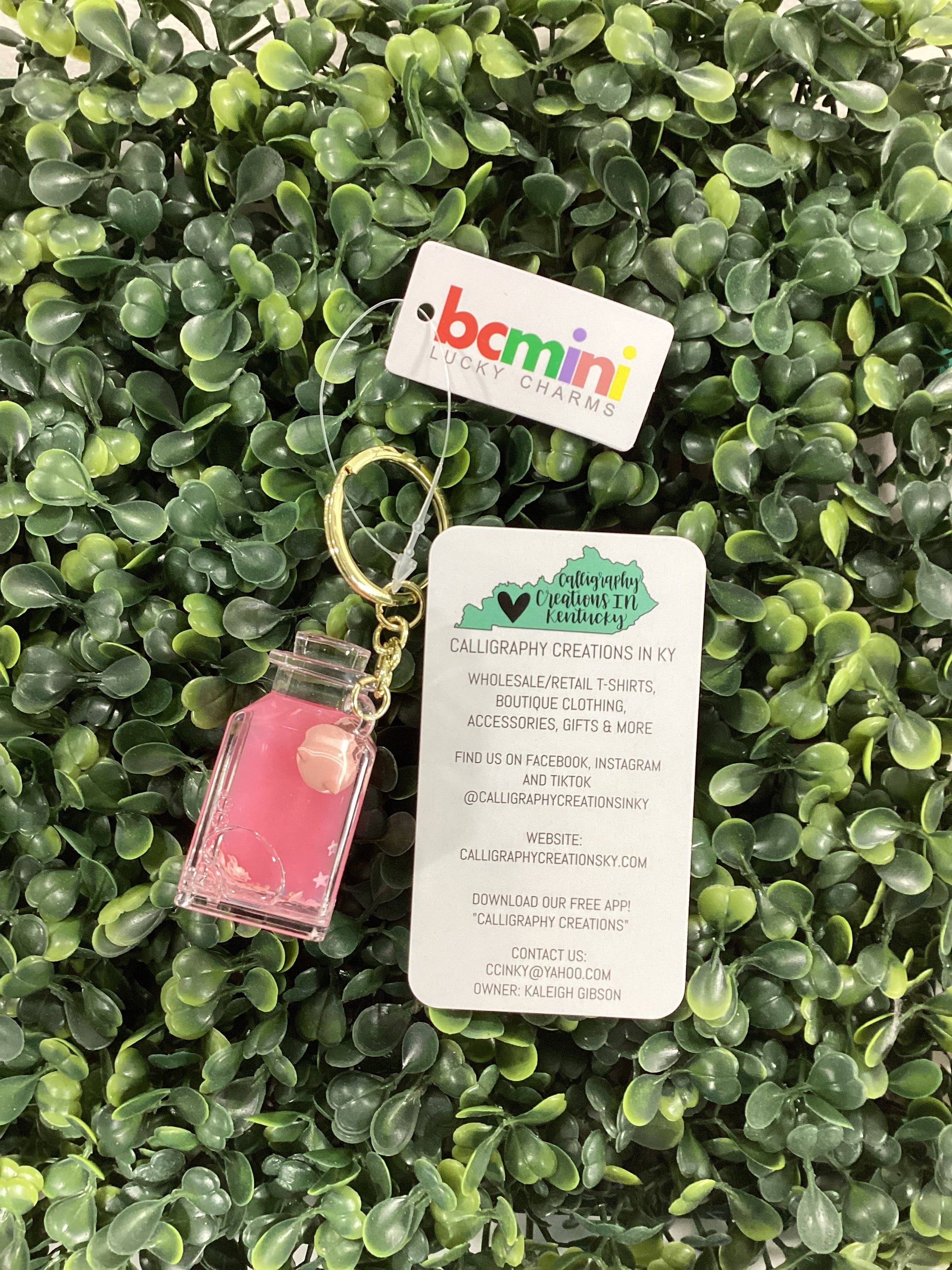 Pink jar keychain on a green leafy background