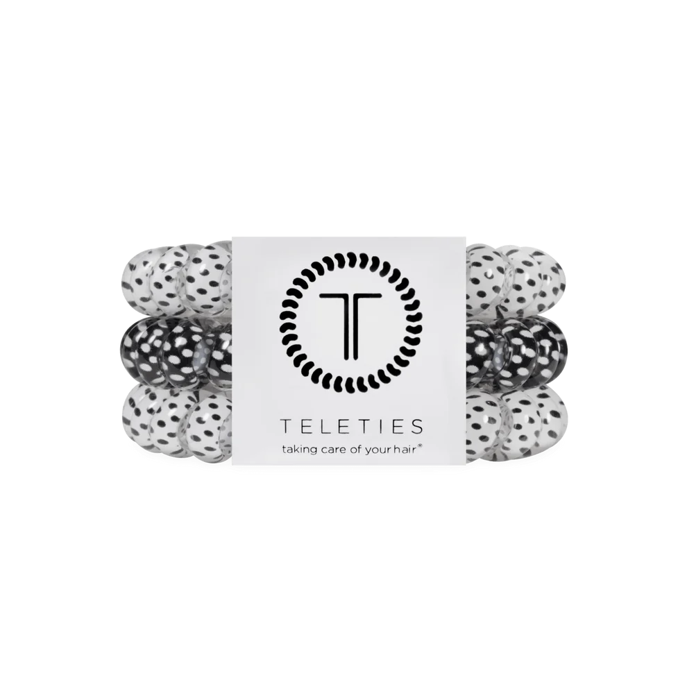 A set of four black and white speckled hair elastic bands wrapped together with a white paper band featuring the TELETIES logo and brand name.