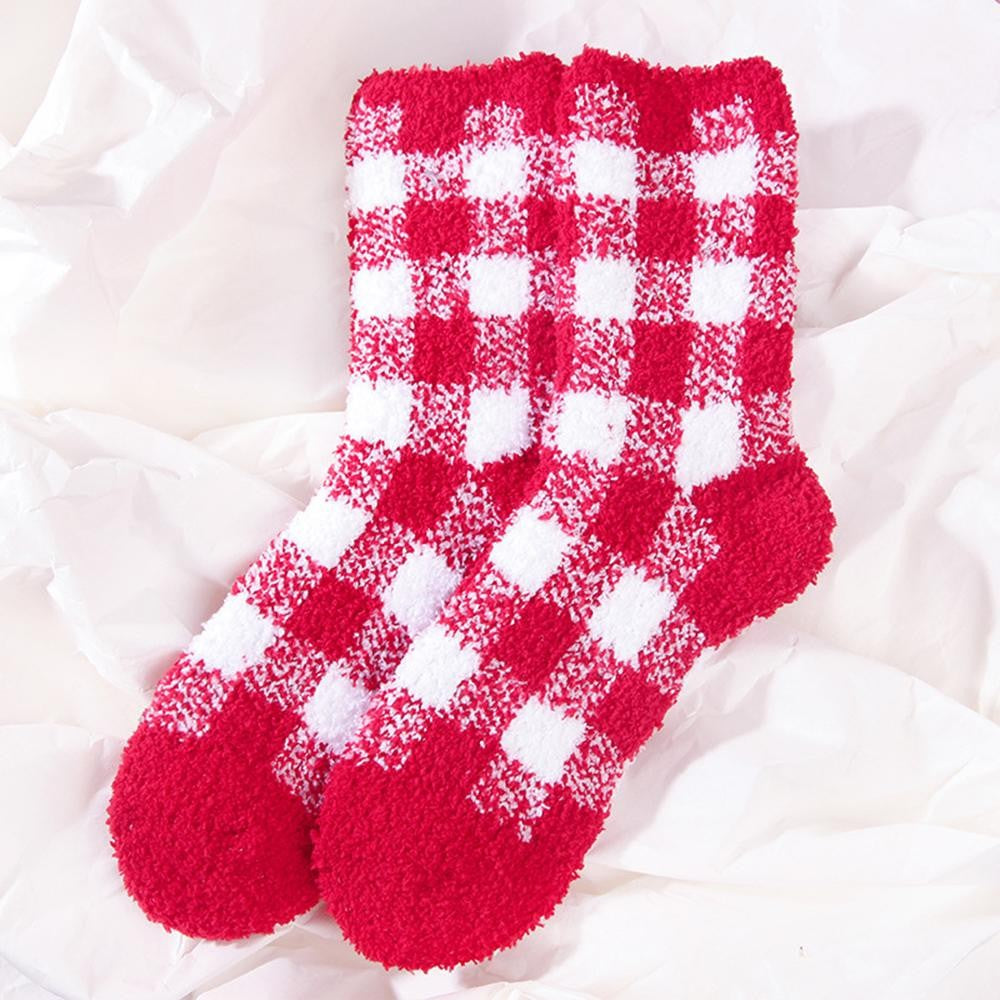 A pair of fuzzy red and white checkered socks laid flat on a white crumpled fabric background.