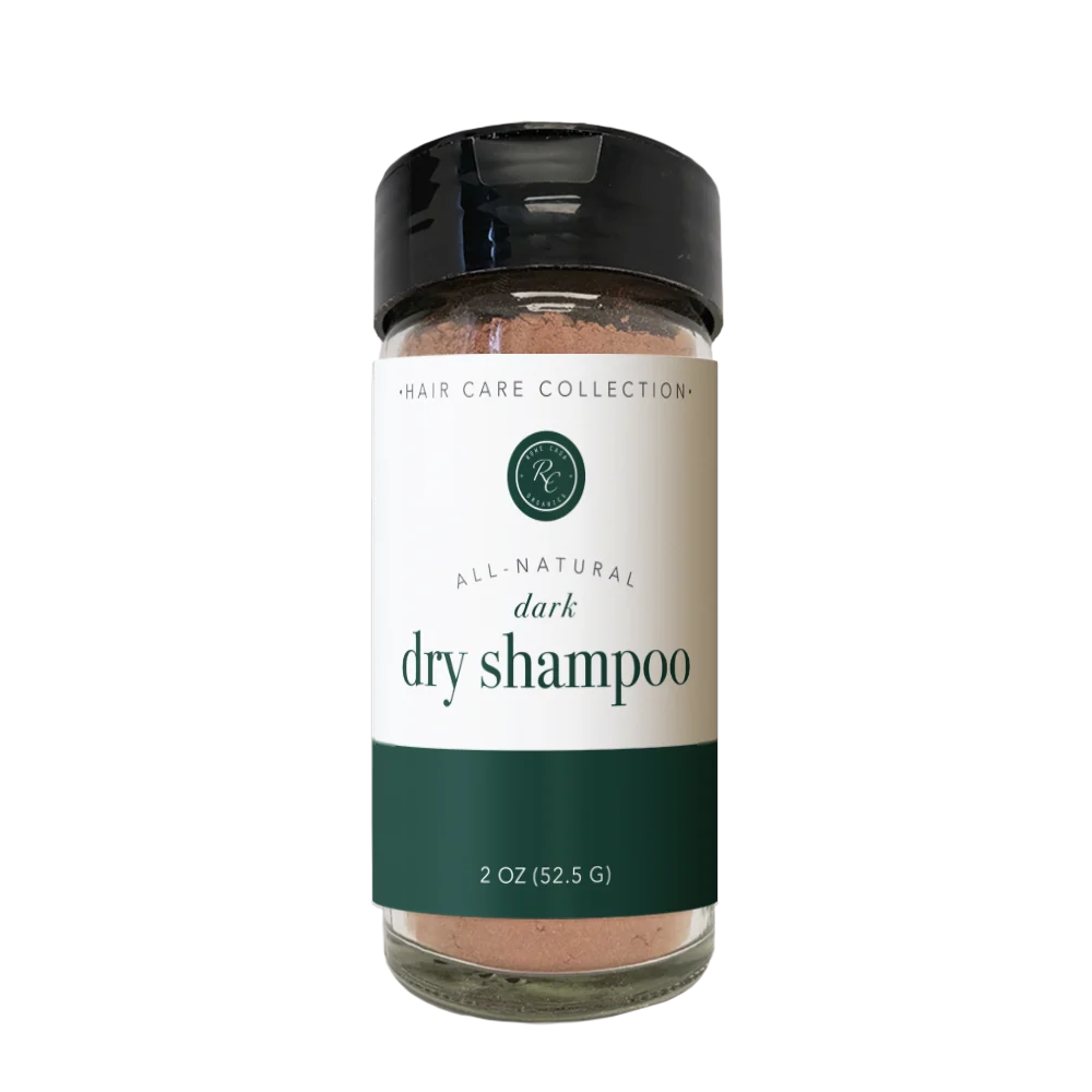 A 2 oz glass bottle of dark dry shampoo from the Hair Care Collection, featuring a black cap and a cream and dark green label.