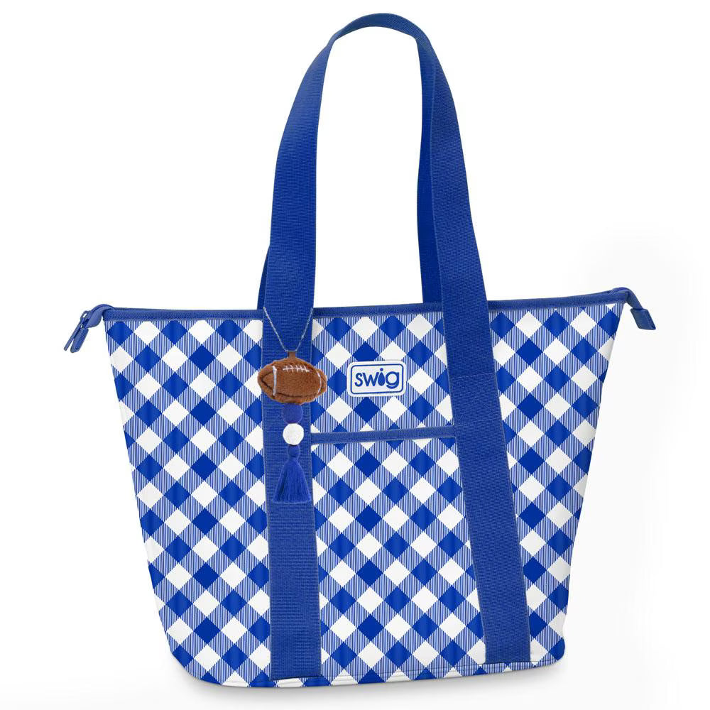 A blue and white gingham tote bag with royal blue handles, a front zip pocket, and a small brown football charm with the Swig logo.