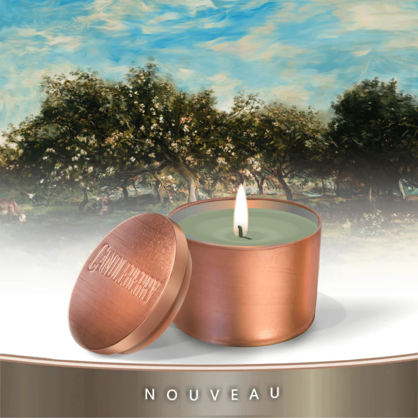 A copper-colored travel tin candle with a green label, set against a serene nature backdrop.