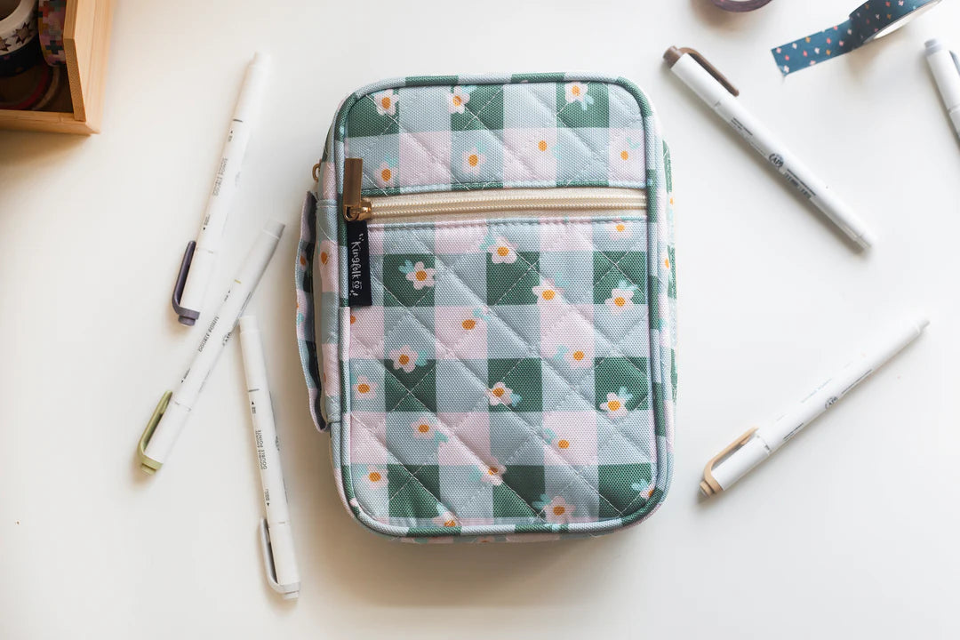 Quilted Bible cover with floral pattern on a white surface with pens