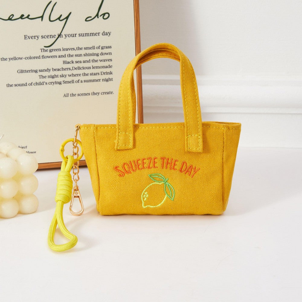 Yellow handbag with 'Squeeze the Day' text and lemon graphic on a white background