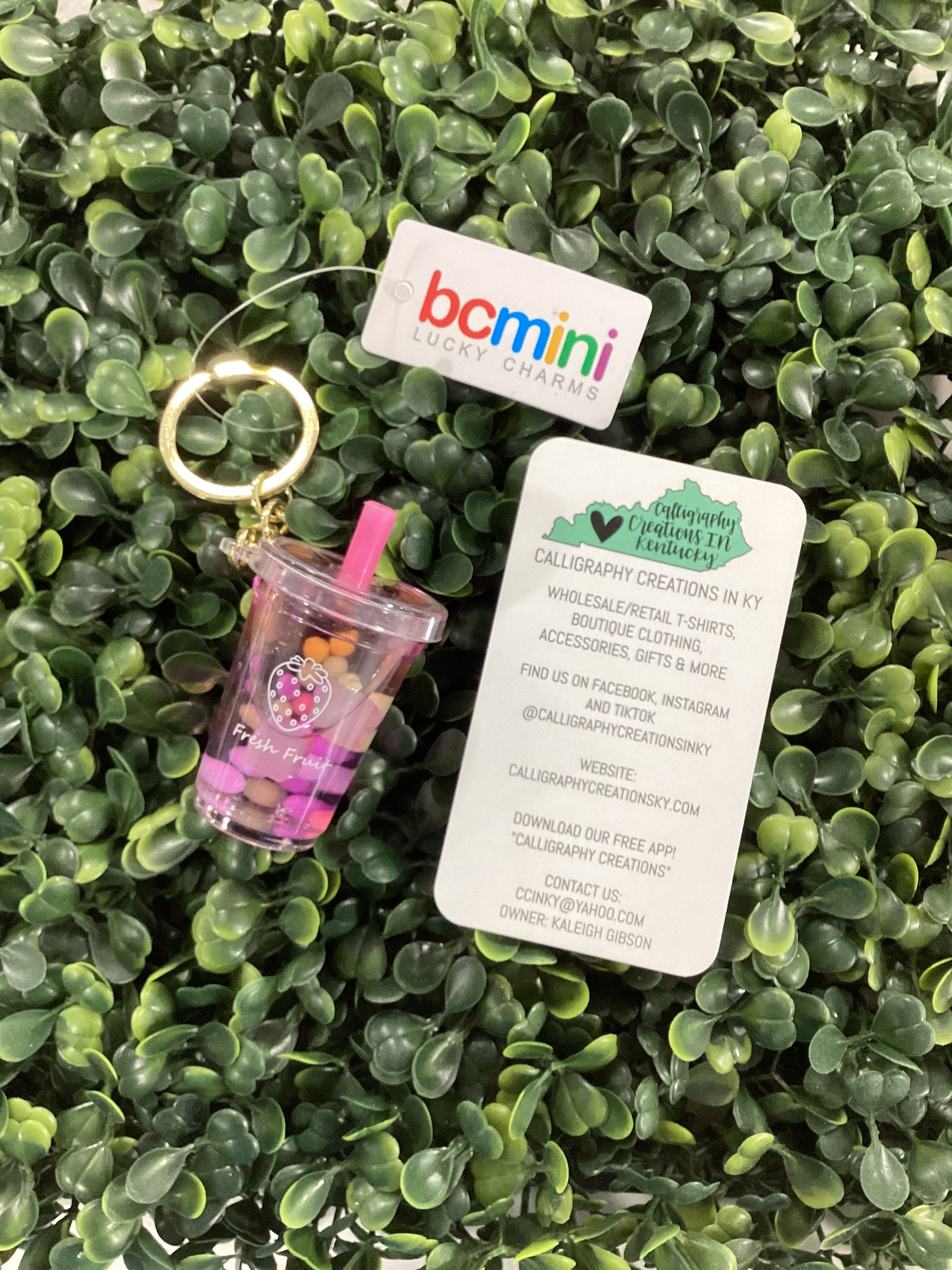 Small pink and clear cup shaped keychain on green artificial grass