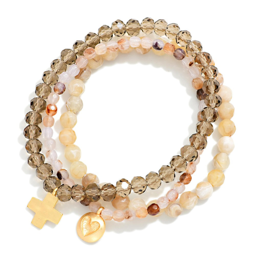 Set of beaded bracelets with gold charms on a white background