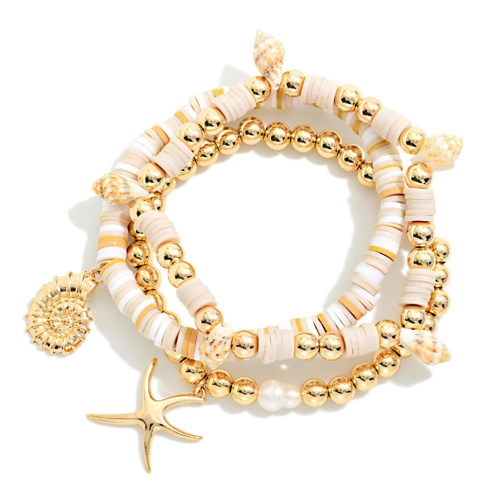 Set of gold and beige beaded bracelets with a starfish charm on a white background