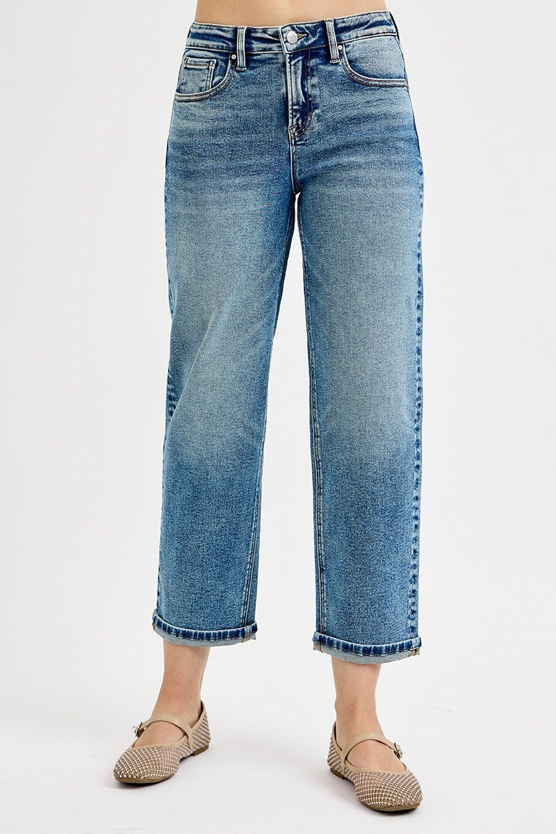 A model from the waist down wearing light blue cropped denim jeans with rolled hems and beige woven flat shoes, photographed against a plain white studio background.