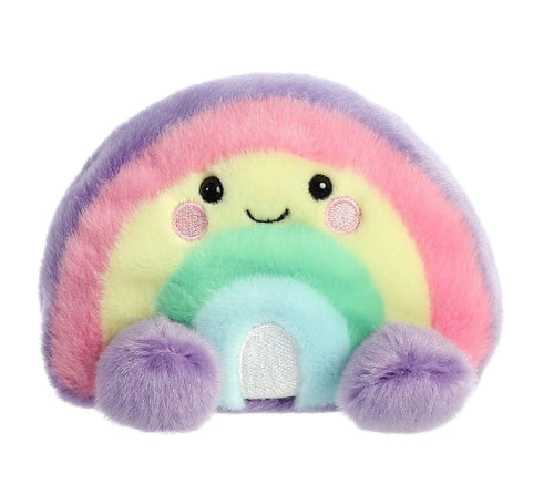 A pastel rainbow plush toy with a cute embroidered face, pink cheeks, and fuzzy purple feet on a plain white background.