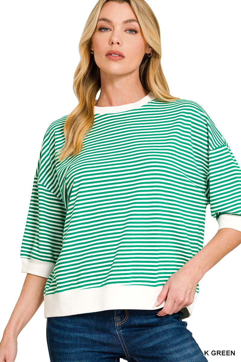 Woman wearing a green and white striped sweater with blue jeans on a white background