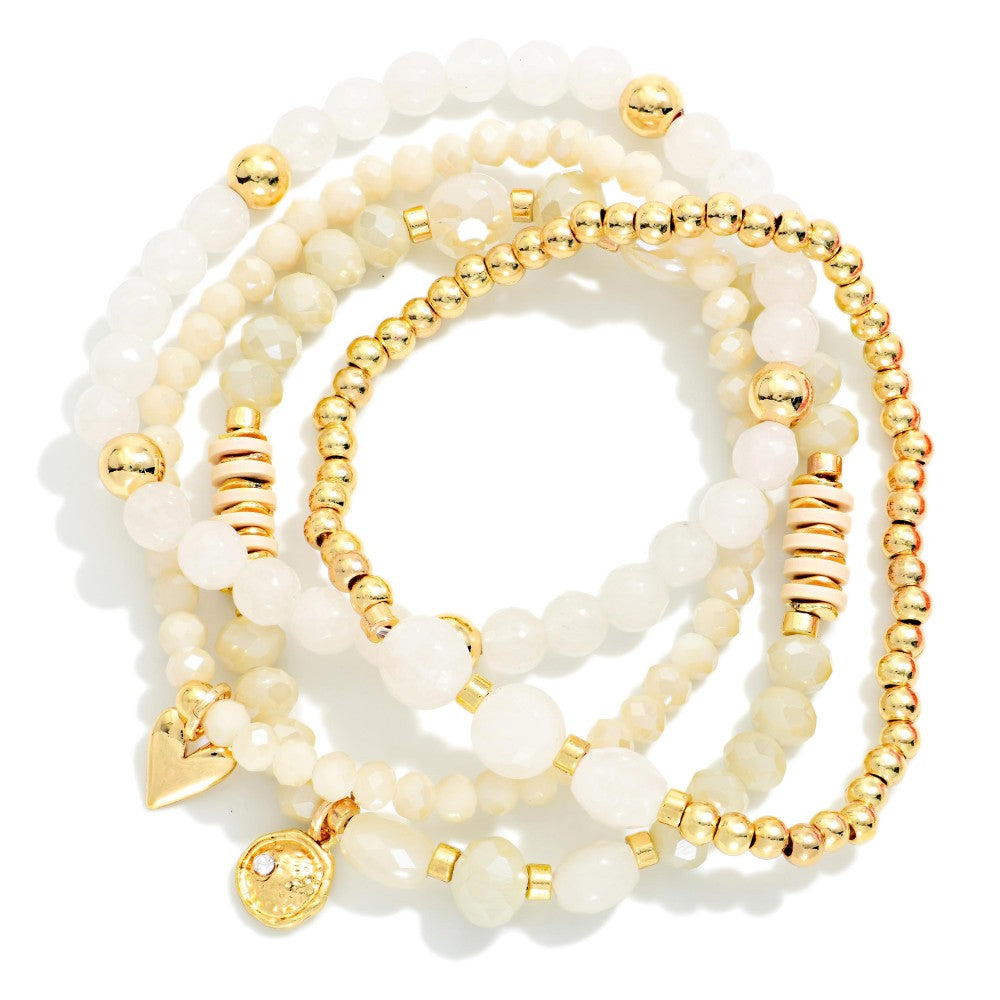 Set of white beaded bracelets with gold accents on a white background
