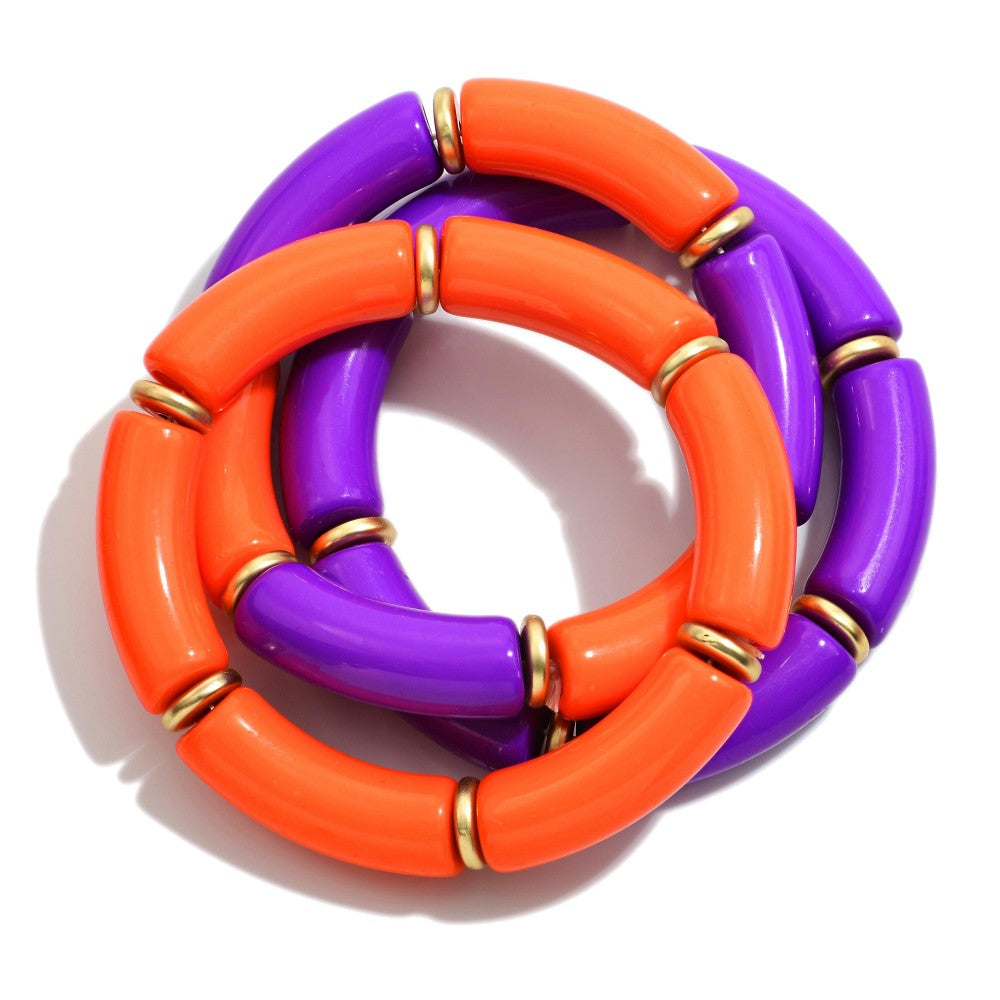 A chunky beaded ring necklace featuring alternating glossy orange and purple cylindrical beads separated by small gold spacer rings, shown on a white background.