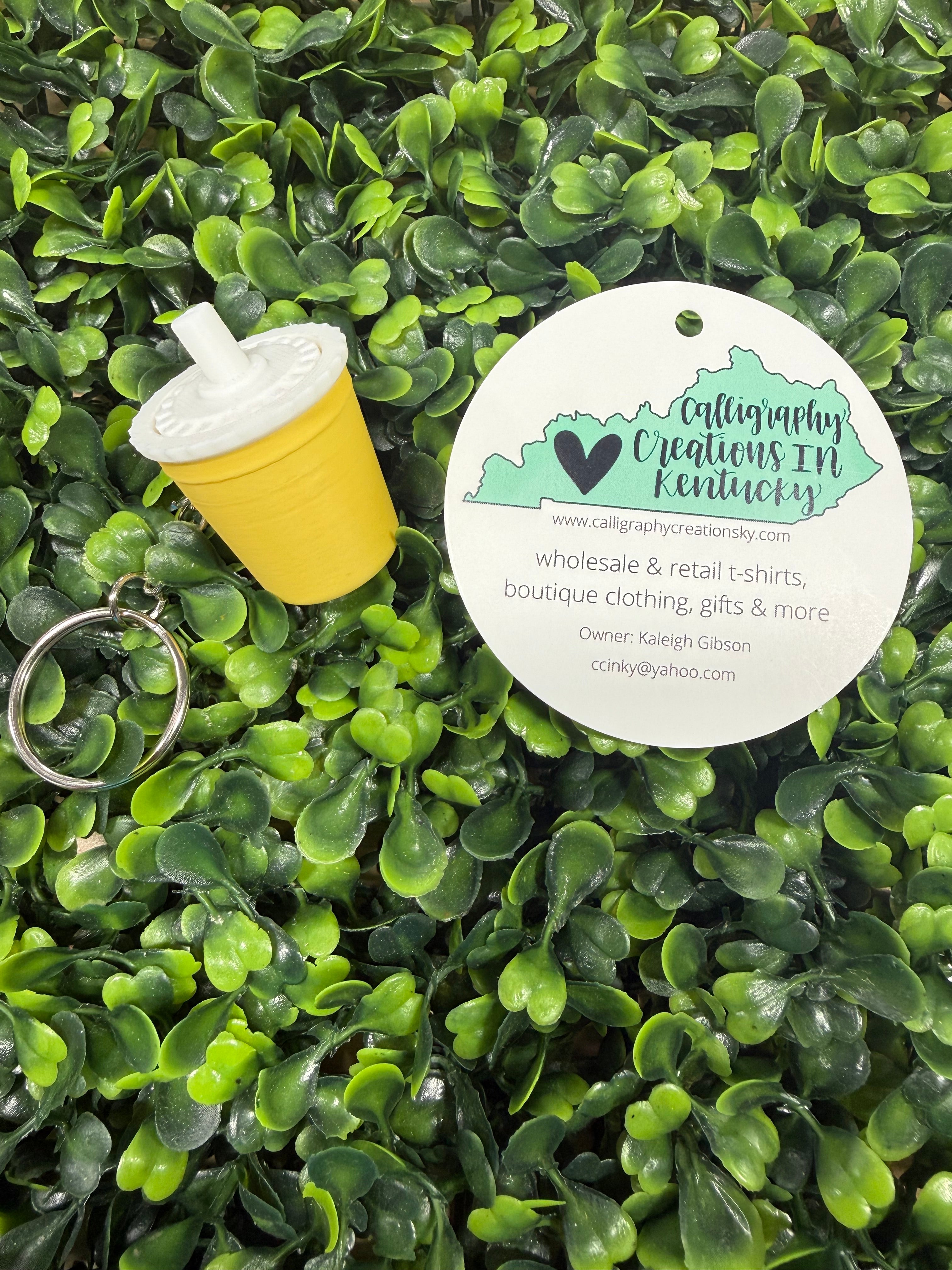 Yellow and white drink fidget with a keychain on green leafy background