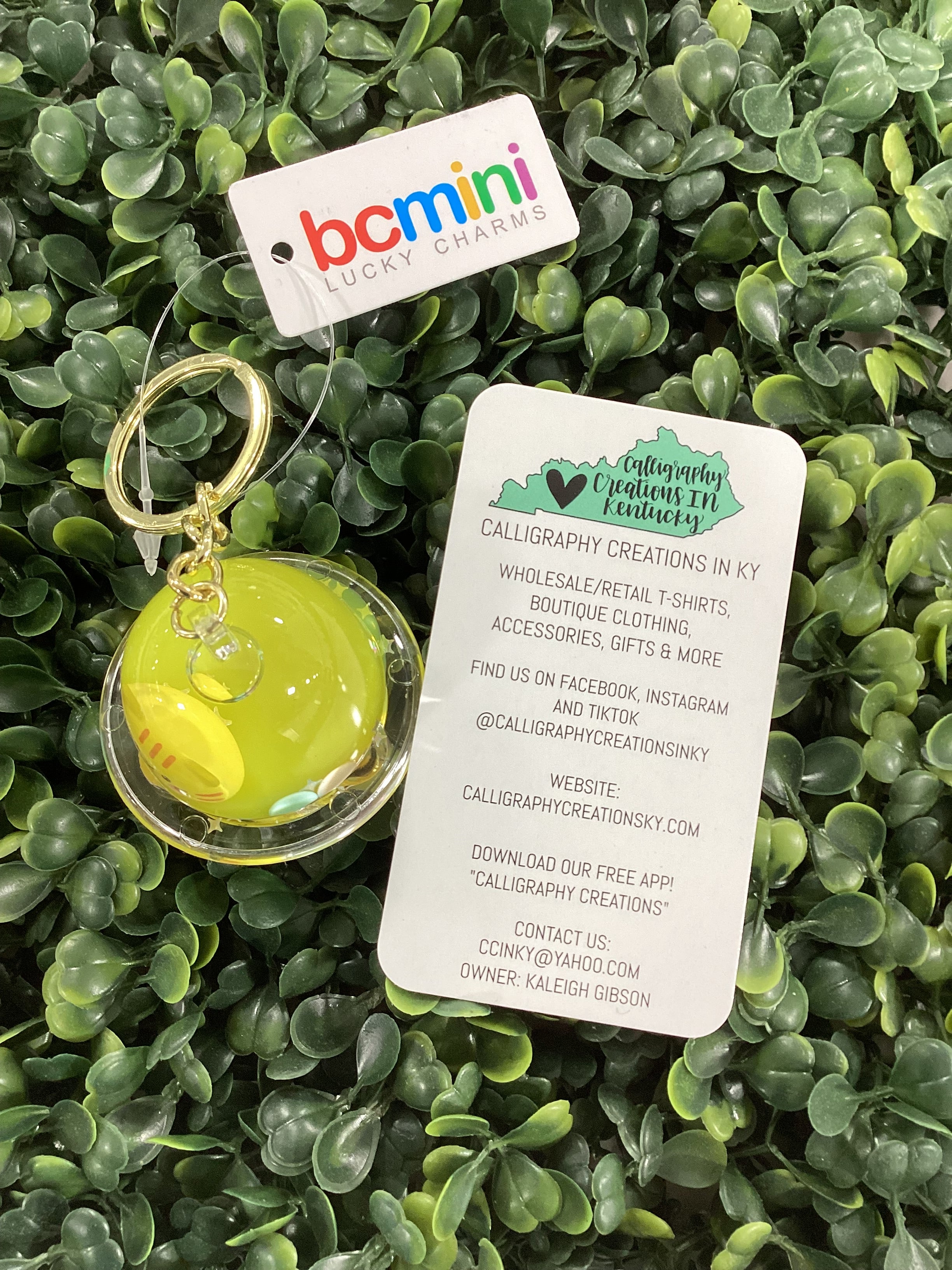 Keychain with clear dome and yellow cat on green leafy background