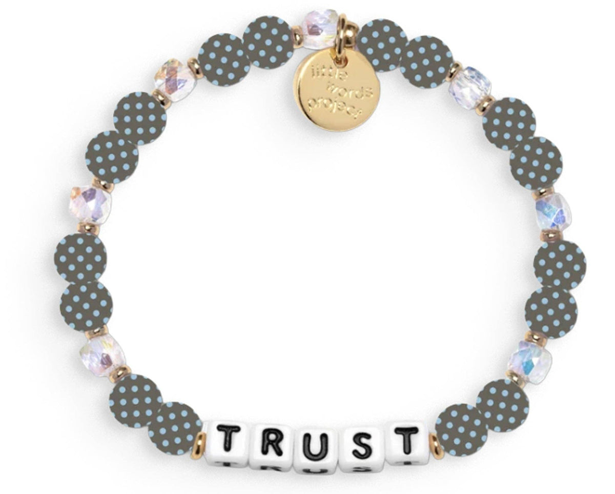 Bracelet with polka dot beads that says "TRUST" and a gold charm on a white background