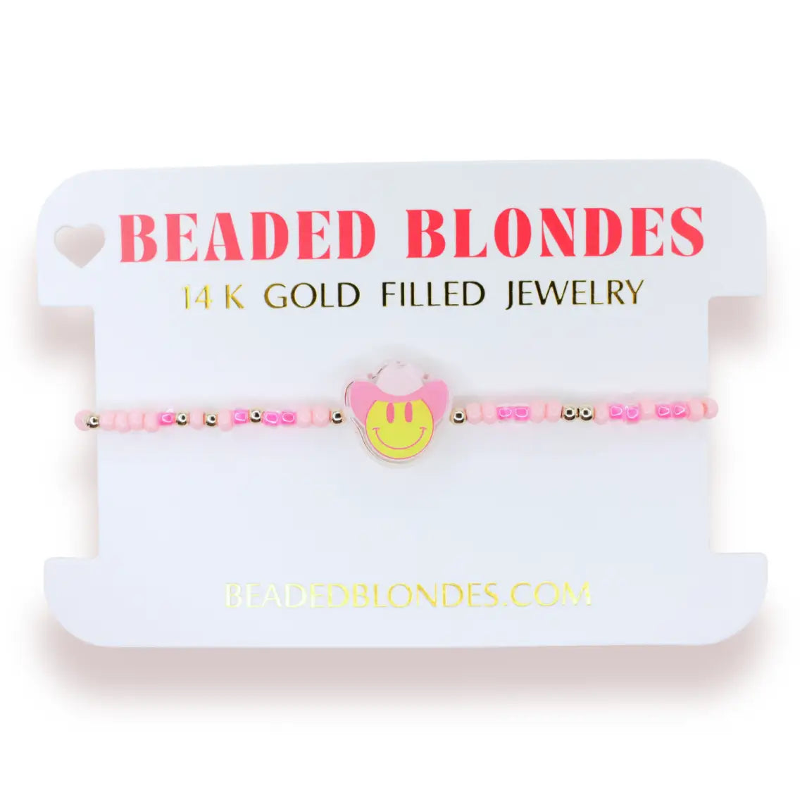 A pink beaded bracelet with a yellow smiley face charm and pink bunny ears, displayed on a white card labeled 'BEADED BLONDES 14 K GOLD FILLED JEWELRY'.